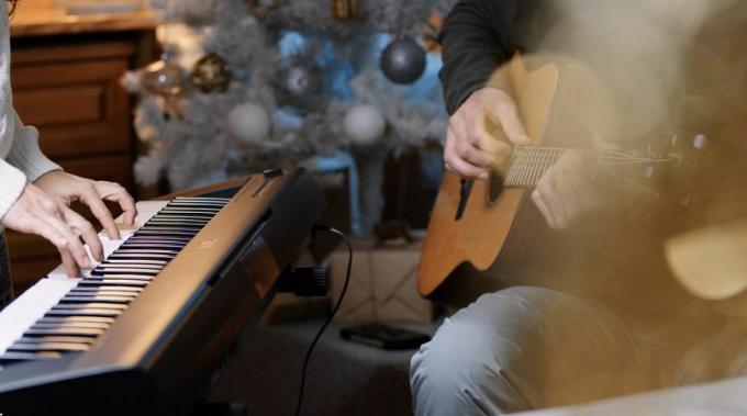 ζευγάρι παίζει μουσική μαζί την παραμονή των Χριστουγέννων στο σπίτι