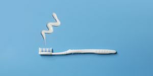 κοντινή όψη μιας επίπεδης άσπρης οδοντόβουρτσας και οδοντόπαστας σε μπλε φόντο