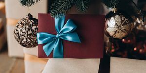 δωροεπιταγή σε μπορντό φάκελο με μπλε φιόγκο κάτω από το χριστουγεννιάτικο δέντρο χριστουγεννιάτικο δώρο